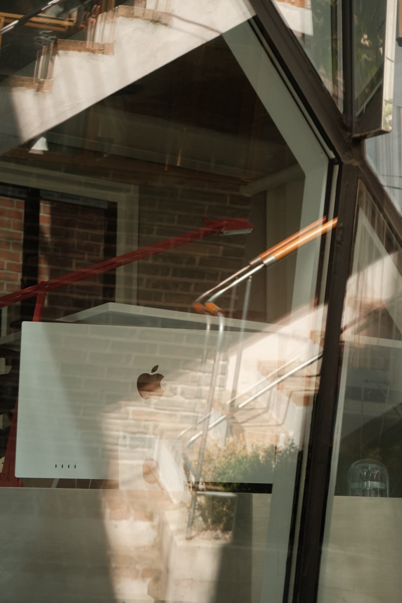 A studio interior reflected in an angled glass facade